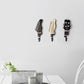 Three guitar-shaped wall hooks in black, cream, and dark gray, each with curved iron hook