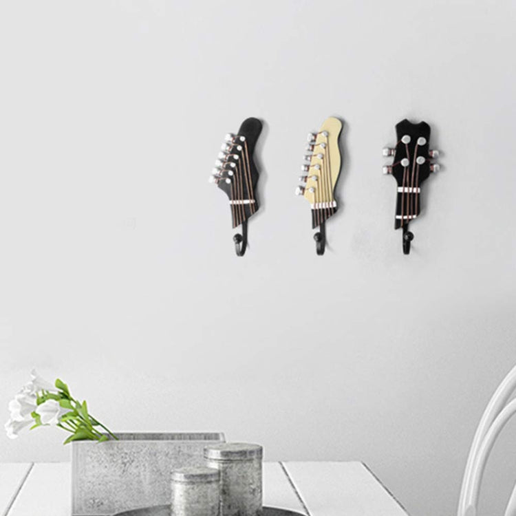 Three guitar-shaped wall hooks in black, cream, and dark gray, each with curved iron hook