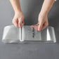 Self-adhesive strap being wrapped around a rolled garment bundle