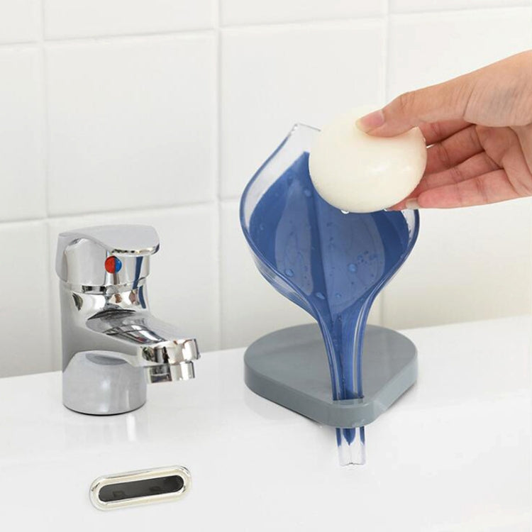 Transparent blue leaf soap holder holding a white bar on a grey suction base