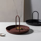 Brown round storage tray with two upright handles, holding small decor items.