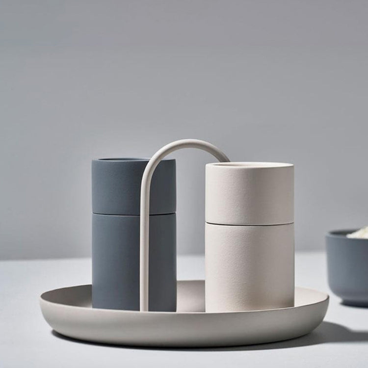 Light gray round tray with two upright handles, holding two canisters.