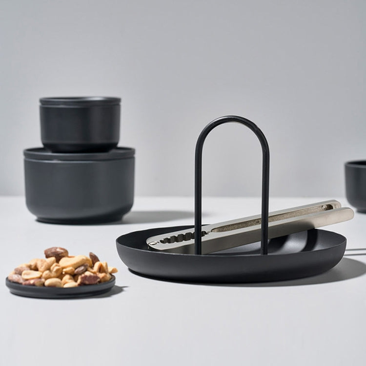 Black round tray with two upright handles, holding a small jar and snack bowl.