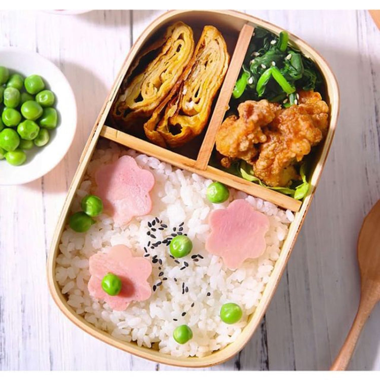Open wooden bento lunch box with divider, holding rice, meat, and garnish
