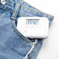 Mini electronic pill box with digital timer resting on blue denim jeans pocket