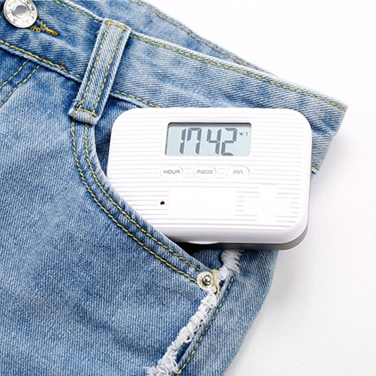Mini electronic pill box with digital timer resting on blue denim jeans pocket