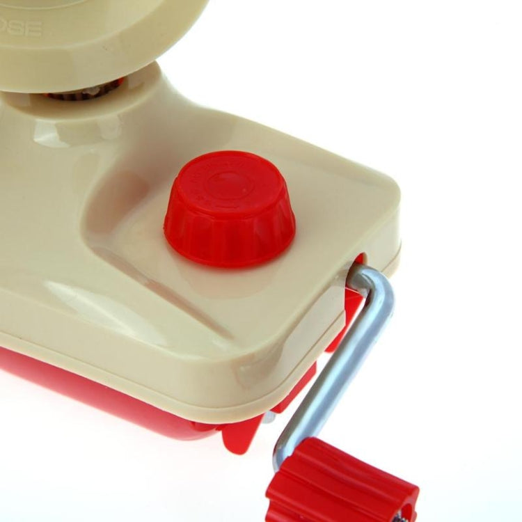 Close-up of beige yarn winding machine with red control cap and metal side handle