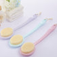 Two round bath scrub brushes with yellow heads on pink and blue long handles