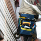 Blue and black electrician tool belt bag on a worker, holding tools and supplies.