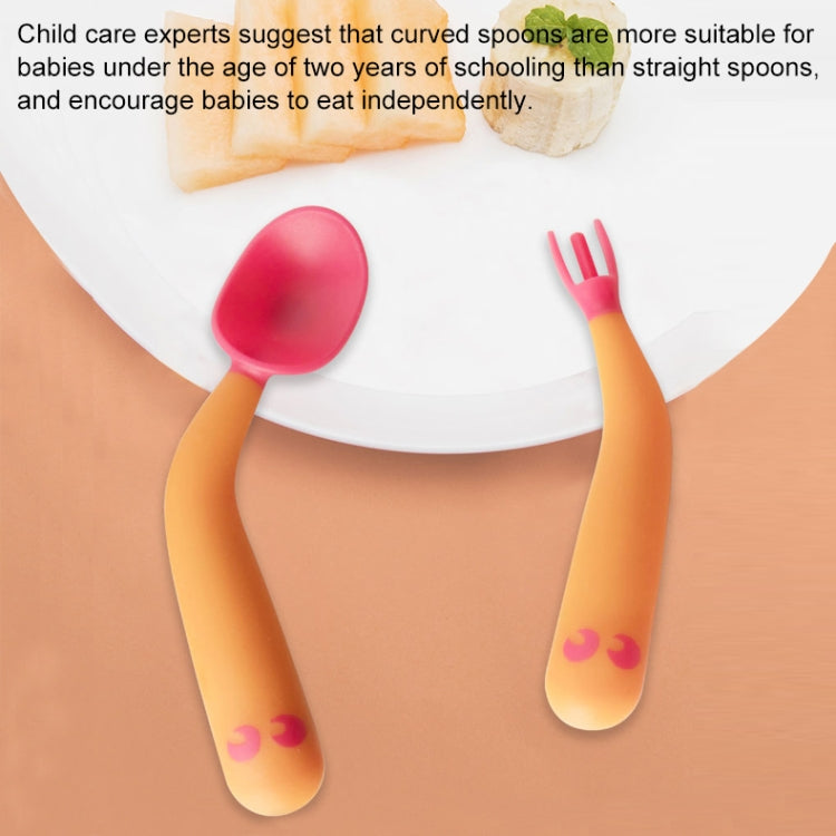 Baby learning curved pink spoons and fork tips with orange handles