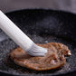 Silicone oil brush spreading oil on a skillet with bristle head