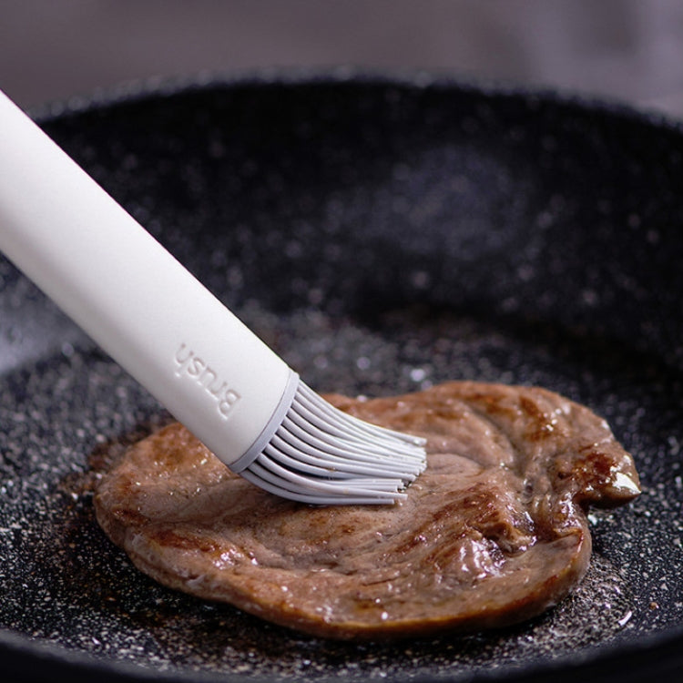Silicone oil brush spreading oil on a skillet with bristle head