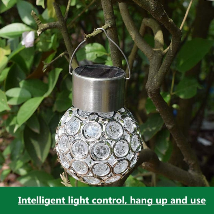 White solar hollow ball pendant lamp hanging outdoors with clear faceted globe