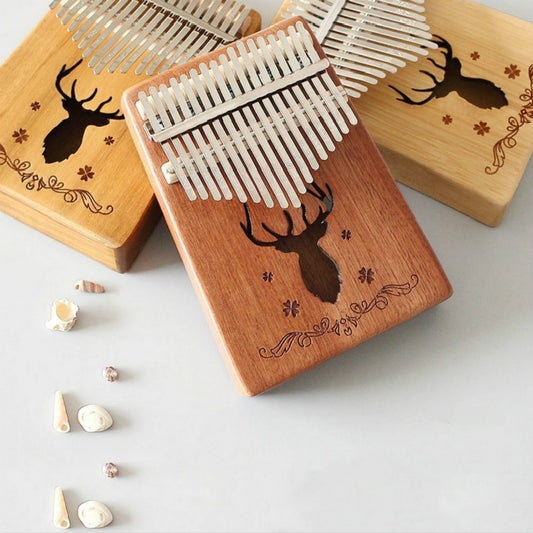 Wooden 17-tone kalimba with deer engraving and white metal tines, angled view