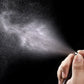 Perfume spray mist from a clear atomizer bottle with black nozzle