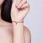 Red adjustable string bracelet with sterling silver star charm on forearm