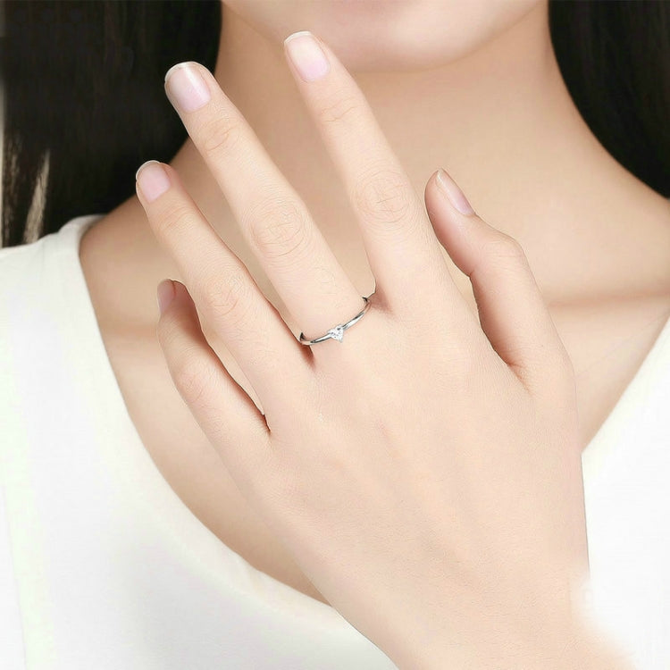 Heart-shaped clear CZ solitaire ring worn on hand with slim silver band
