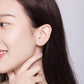 Sterling silver dog bone stud earrings on model with hand near ear