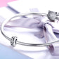 Sterling silver flower-pattern bead charm on a braided bracelet chain with bow