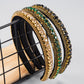 Rhinestone headband with gold edging, green and black stone rows, black base