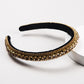 Black velvet rhinestone headband with gold trim and green accents