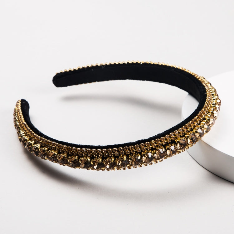 Black velvet rhinestone headband with gold trim and green accents