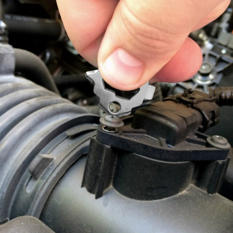 Key ring multi-tool engaged on a vehicle headlight assembly fastener