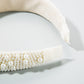 Close-up of white pearl beaded band with cream fabric backing and stitched end.