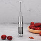Stainless steel date pitting device standing on counter near dates