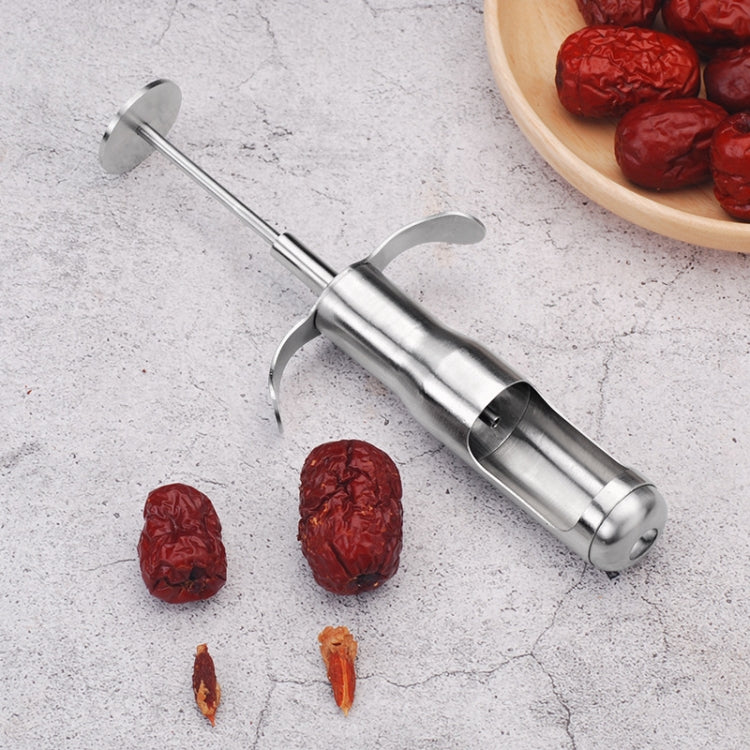 Stainless steel date pitting device with red tip and curved handles on countertop