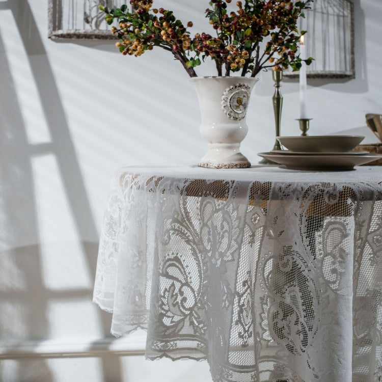 Close-up of white lace tablecloth with embossed floral scroll pattern