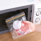 Clear sealed food storage bag with orange stripe top, holding raw meat