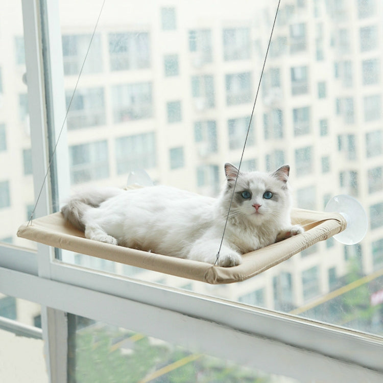 Cat resting on window-mounted suction cup cat hammock with tan fabric platform