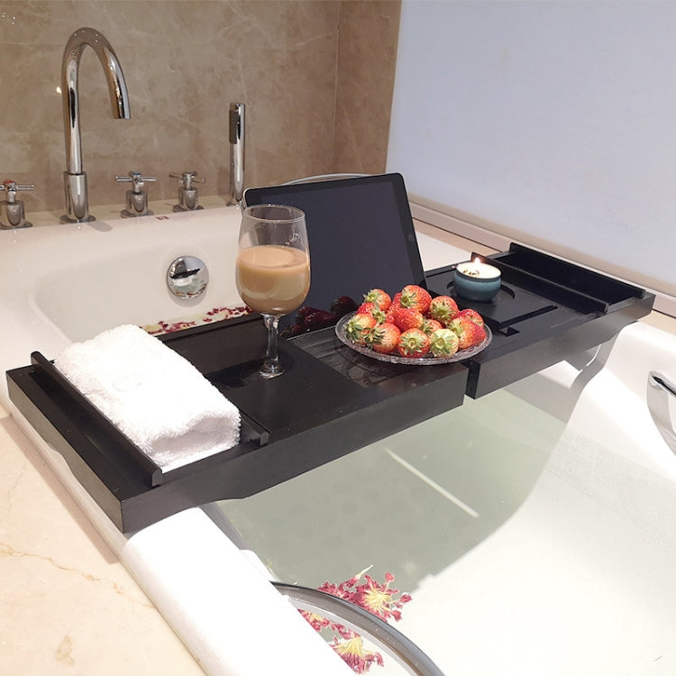 Black retractable bathtub shelf rack holding a drink, candle, and fruit tray