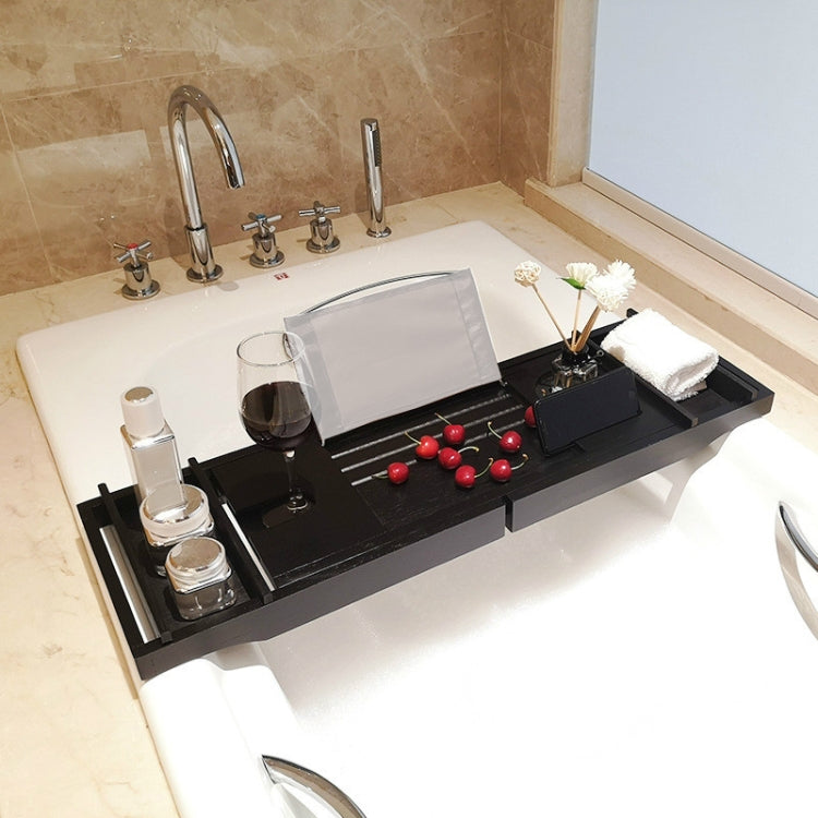 Black bathtub shelf rack on a white tub with towels, drinkware, and candle