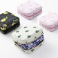 Stacked square zip sanitary napkin storage pouches in pink, white, and black patterns