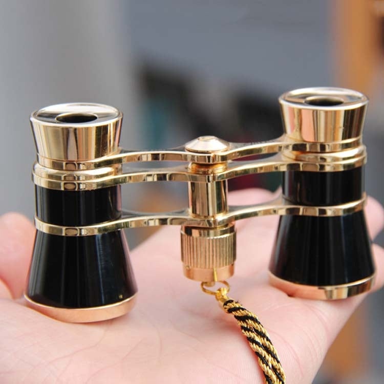 Compact opera binoculars with gold frames and black barrels, plus braided chain