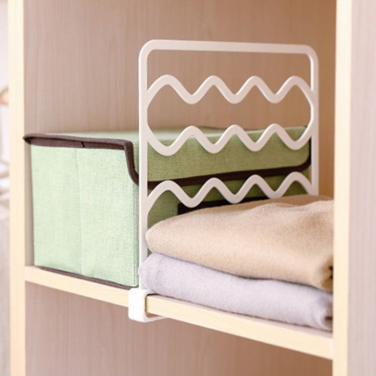 White wave shelf divider bar holding folded towels and folded cloth items