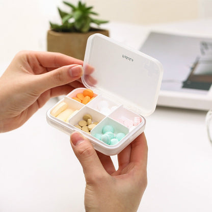 Portable pill box with hinged lid open, showing 6 divided compartments with assorted tablets