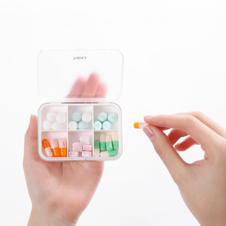 White pill box with clear hinged lid open, showing divided compartments and colorful pills