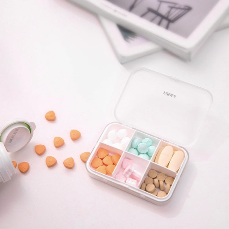 Sealed mini pill box open with grid compartments filled with multicolored tablets