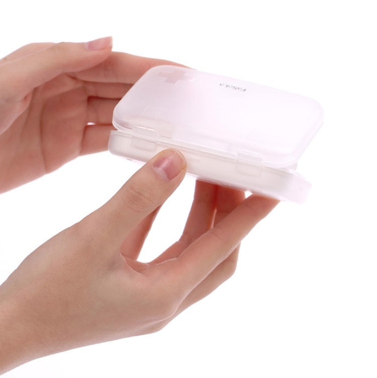 Small white sealed pill box with hinged lid held in hands, compact rectangular design