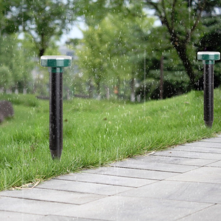 Solar mouse repeller stakes in green-capped form on outdoor lawn with rain