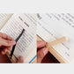 Wooden book stand with black clip holding pages, light natural wood frame