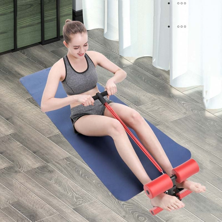Red abdominal curler sit-up aid with handle straps, shown on exercise mat