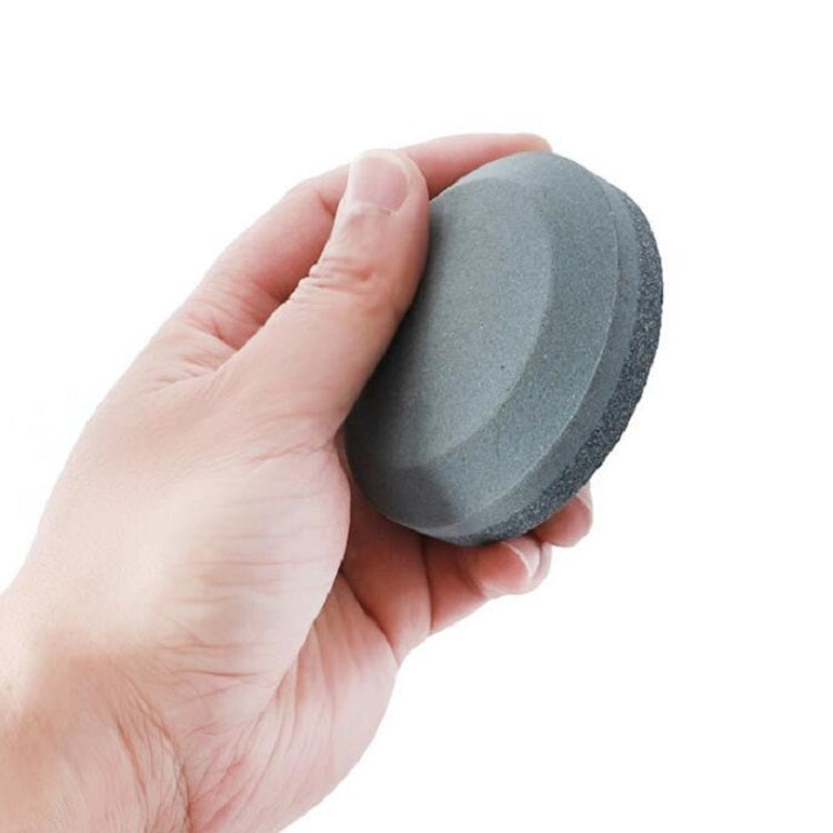 Round dark gray whetstone knife sharpener held in hand
