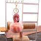 Flamingo plush keychain pendant with pink body and fluffy light-orange pom pom, dangling feet