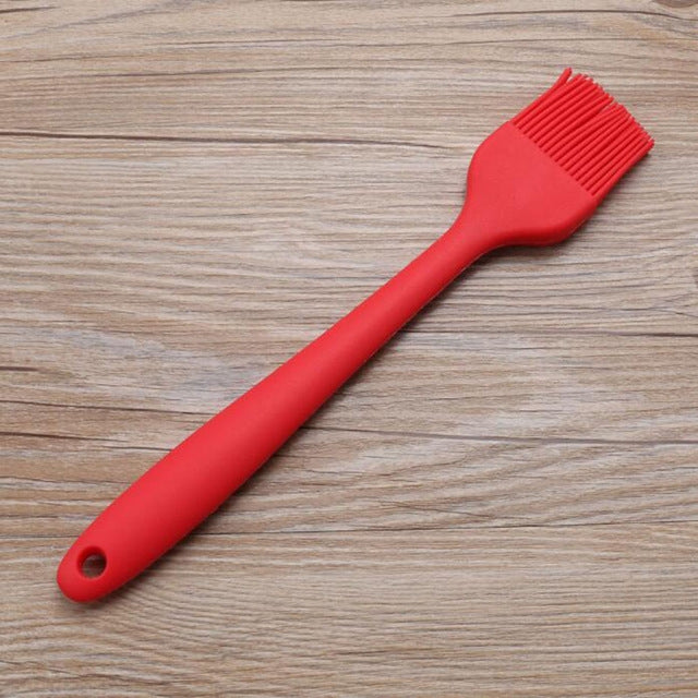 Red silicone oil basting brush with flexible bristle head and hanging hole handle.