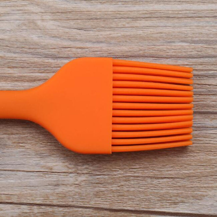 Orange silicone basting brush with wide fan bristle head and short handle grip.