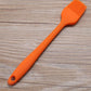 Orange silicone oil basting brush with fan bristle head and hanging hole handle.